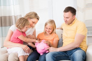 Family Saving Money In Piggybank At Home