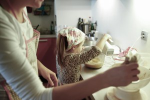Pregnant woman and little girl cooking in the kitchen