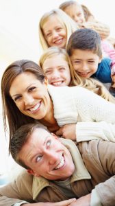 Couple with four children having fun by lying on each other and looking at you